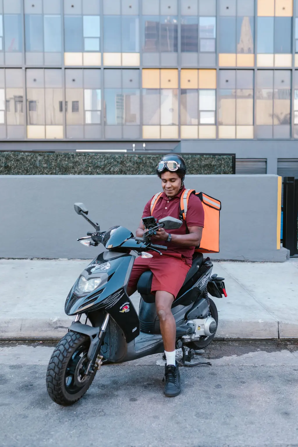 A delivery rider on a scooter checking his phone