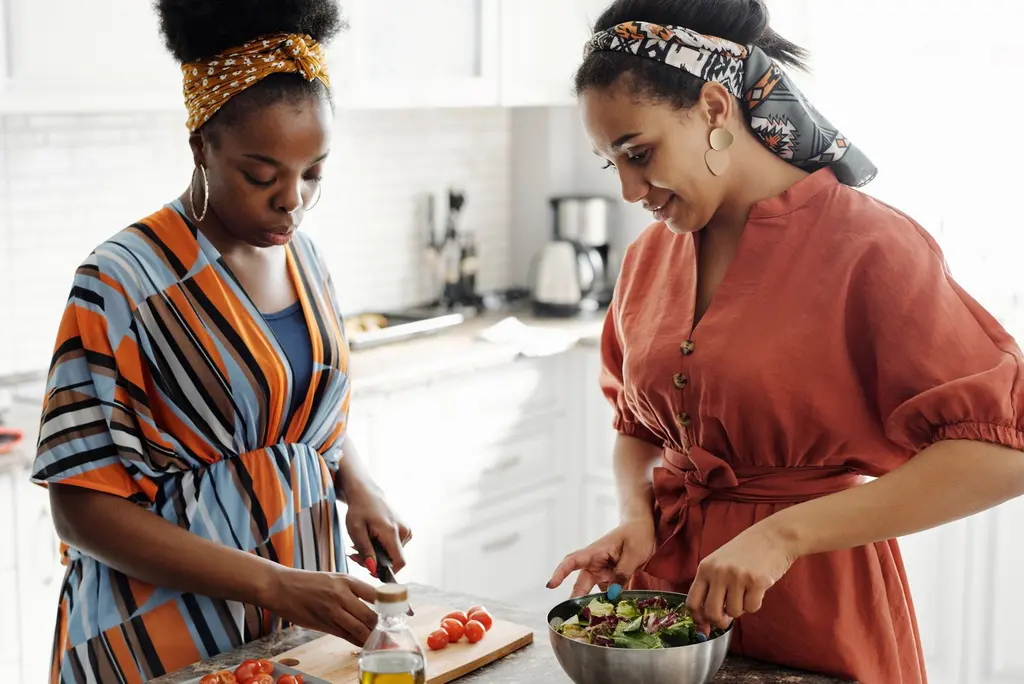 Two women making a salad together in a bright kitchen